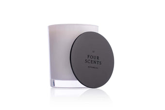 Four Scents Candle With Black Embossed Candle Lid Resting Against it